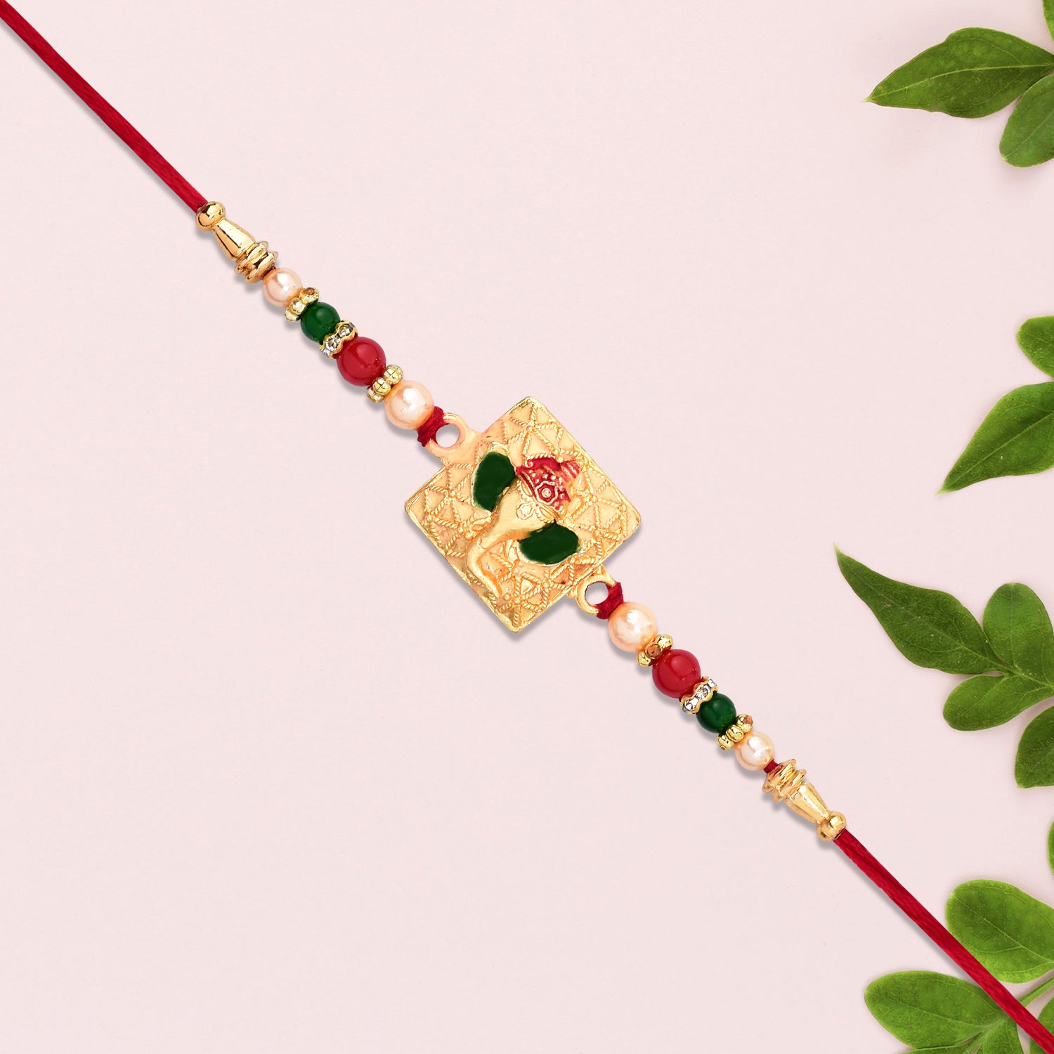 Golden Ganpati Rakhi With Red-green Beads And Enamel Detailing Golden Ganpati Rakhi With Red-green Beads And Enamel Detailing